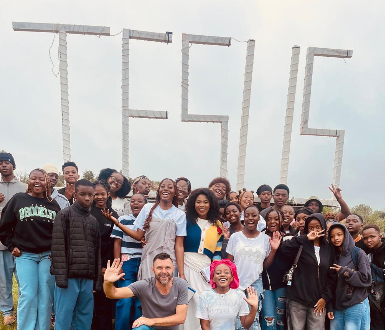 Group photo in front of the JESUS sign on the Solid Ground grounds.