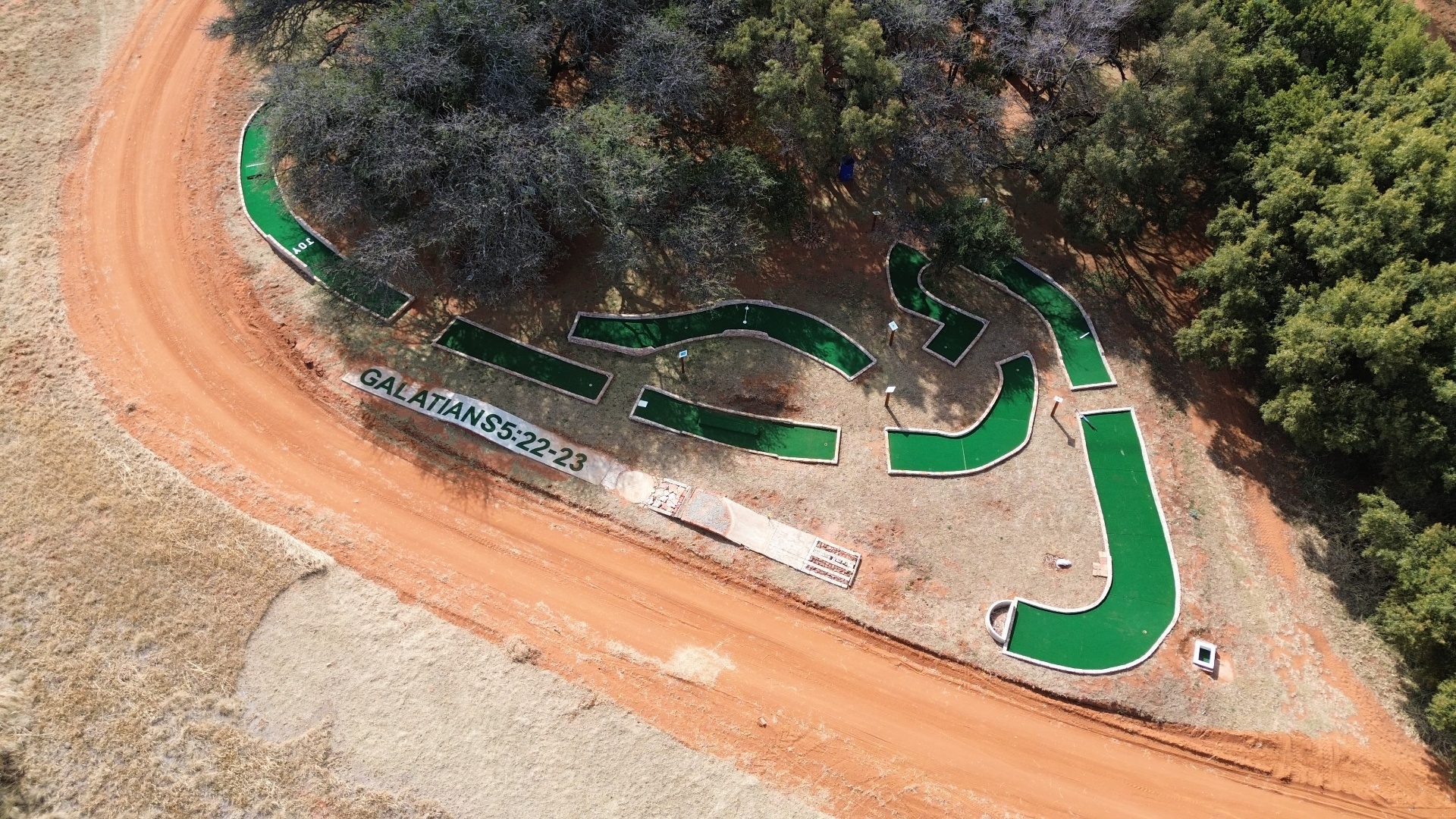 Aerial view of the Fruit of the Spirit mini golf course at Solid Ground, with Galatians 5:22-23 displayed alongside the green holes.